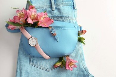 Photo of Flat lay composition with stylish bump bag and spring flowers on light background