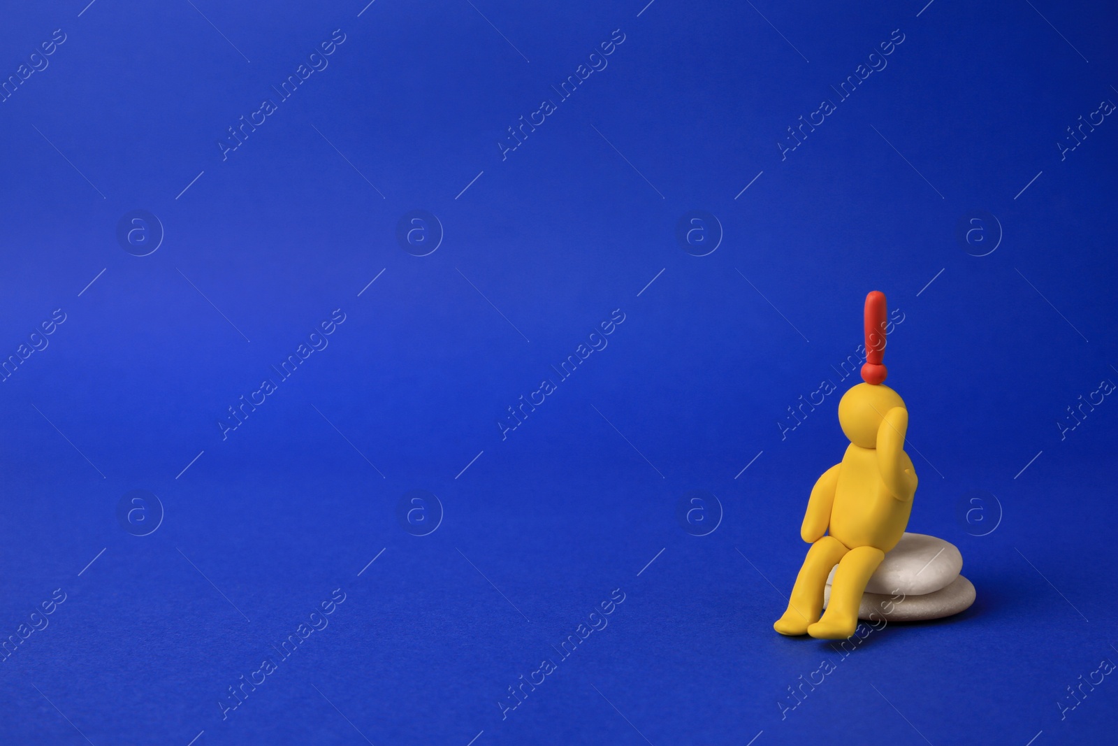 Photo of Human figure made of yellow plasticine with exclamation mark as solution idea on blue background. Space for text