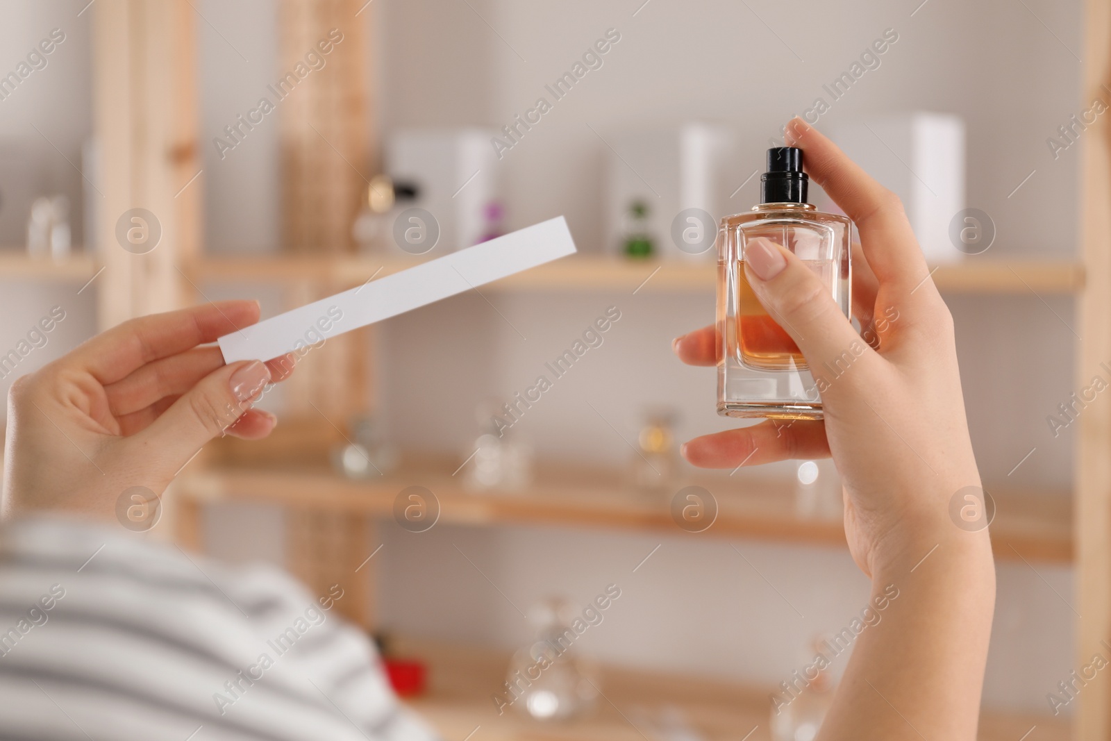 Photo of Woman with bottle of perfume and blotter indoors, closeup