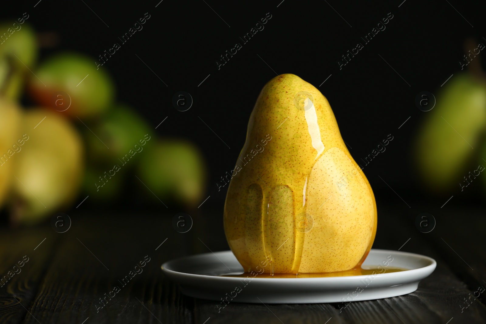 Photo of Plate with fresh ripe pear and sweet syrup on table against blurred background