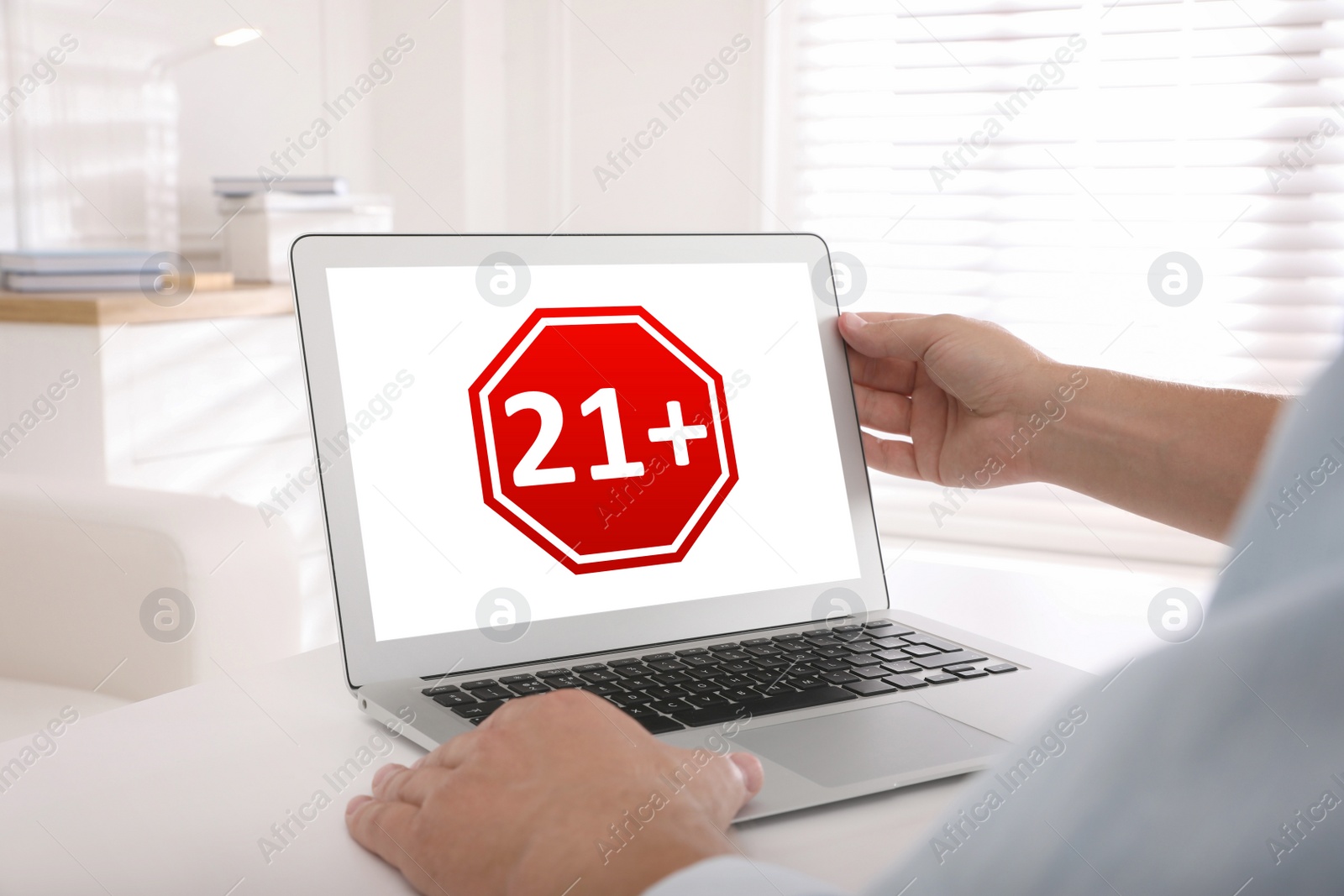 Image of Man using laptop with age limit sign 21+ years indoors, closeup
