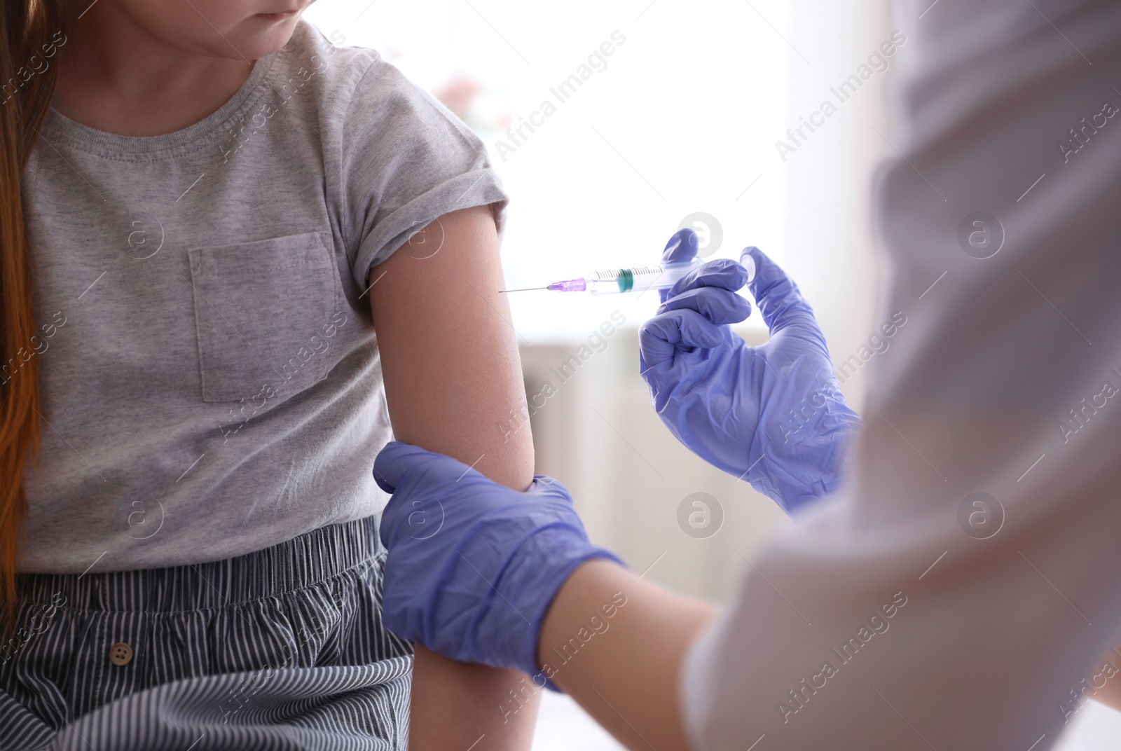 Photo of Little girl receiving chickenpox vaccination in clinic, closeup. Varicella virus prevention