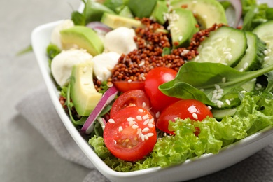 Photo of Delicious avocado salad with quinoa on light grey table, closeup