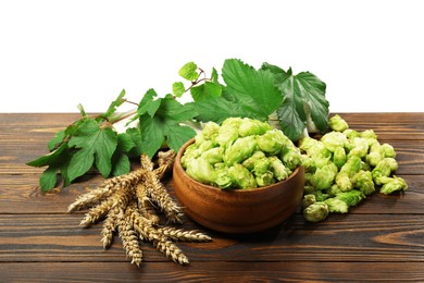 Photo of Fresh hop flowers and wheat ears on wooden table against white background