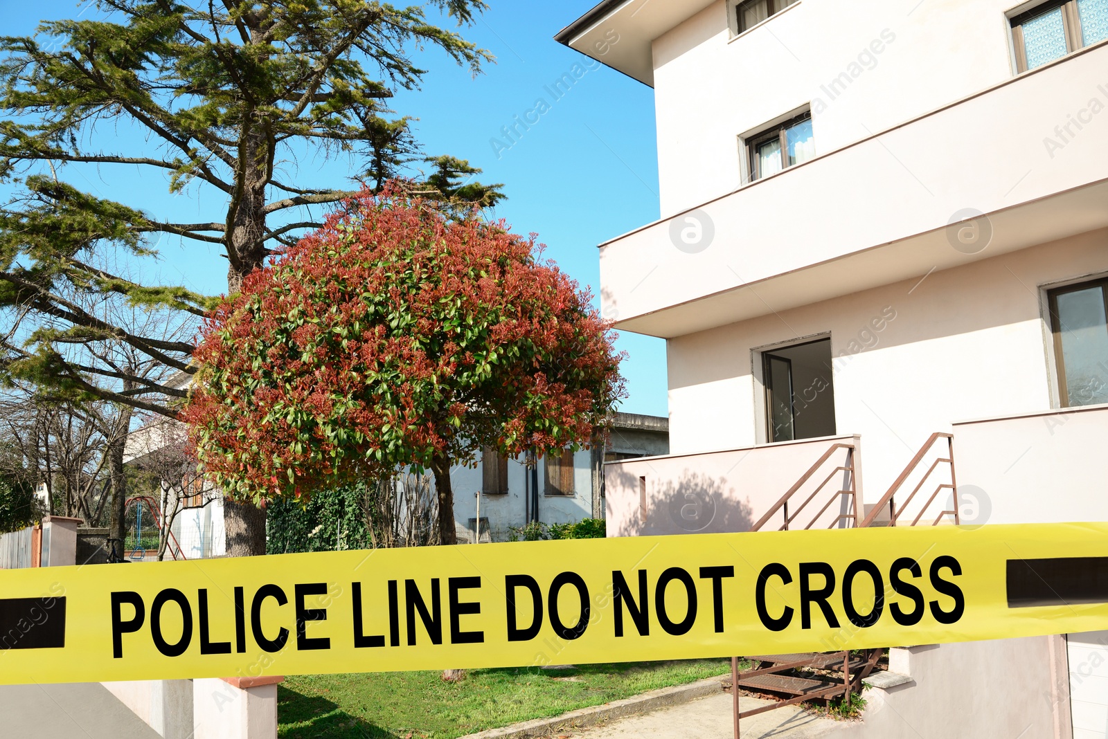 Image of Yellow crime scene tape blocking way to house outdoors