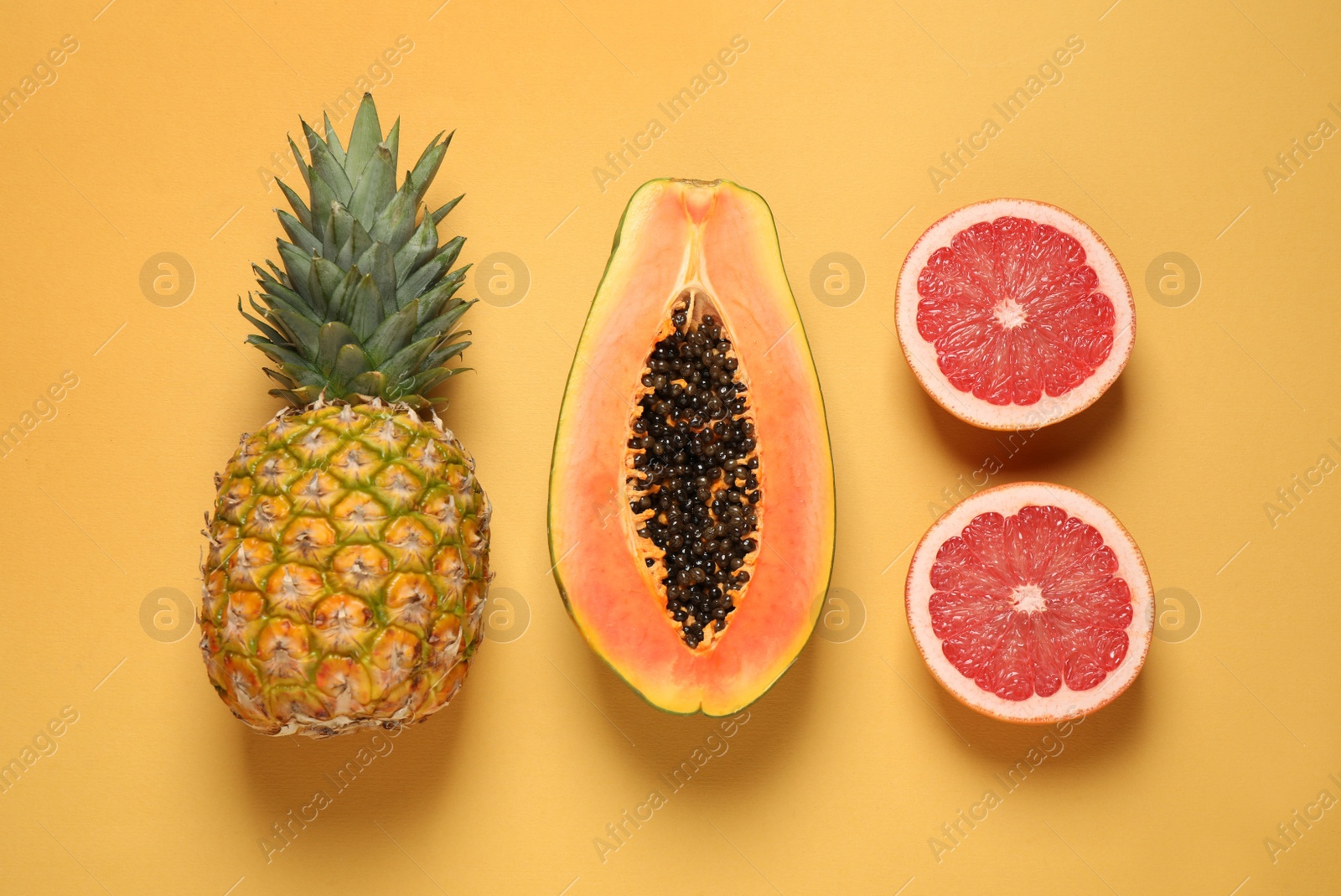Photo of Fresh ripe papaya and other fruits on yellow background. flat lay