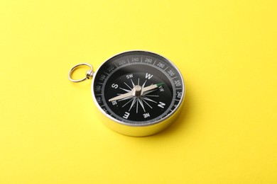 Photo of One compass on yellow background. Tourist equipment