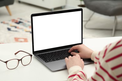 Woman using laptop at white table indoors, closeup