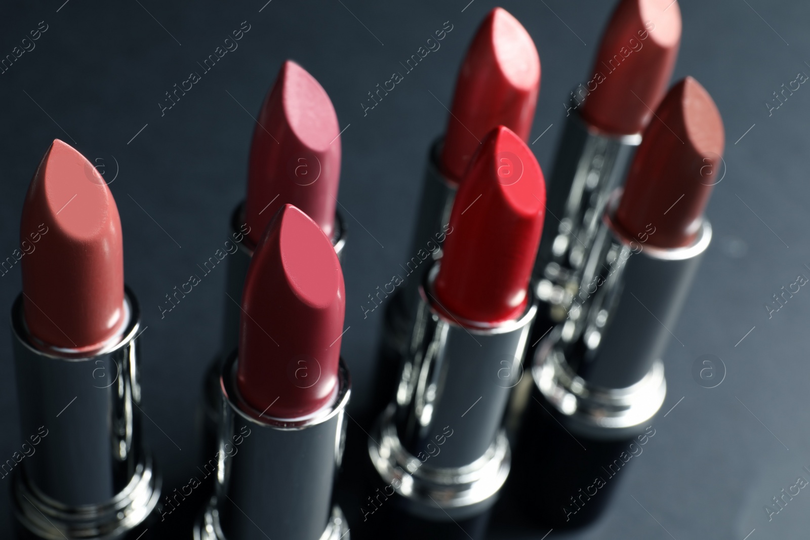 Photo of Set of different lipsticks on grey background, closeup. Cosmetic product