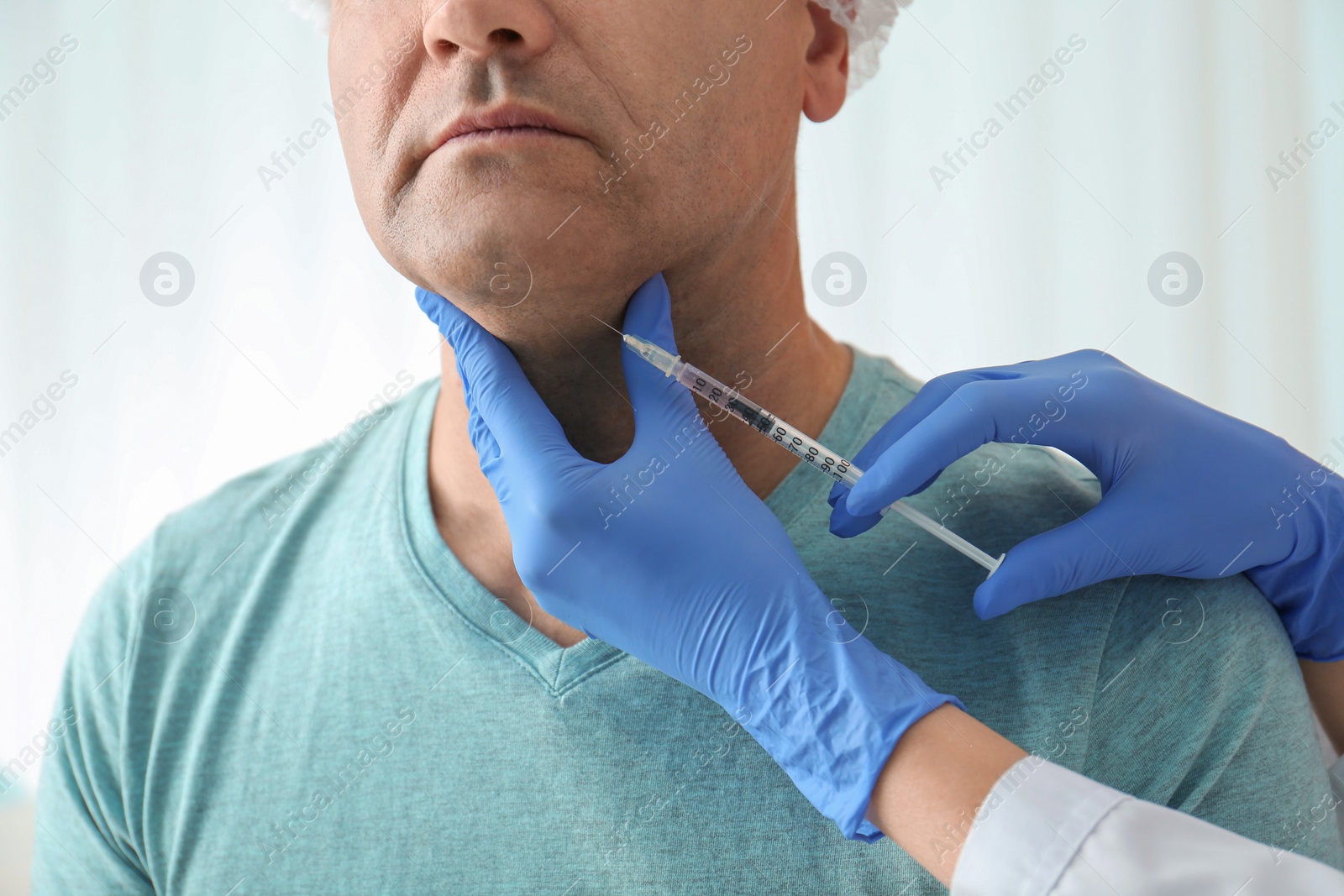 Photo of Mature man with double chin receiving injection in clinic, closeup