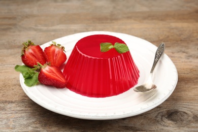 Photo of Plate of tasty strawberry jelly served on wooden table