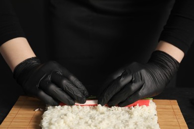Photo of Chef in gloves wrapping sushi roll, closeup