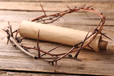 Photo of Crown of thorns and old scroll on wooden table, closeup