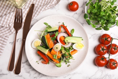 Photo of Salad with fresh organic microgreen in plate on white marble table, flat lay