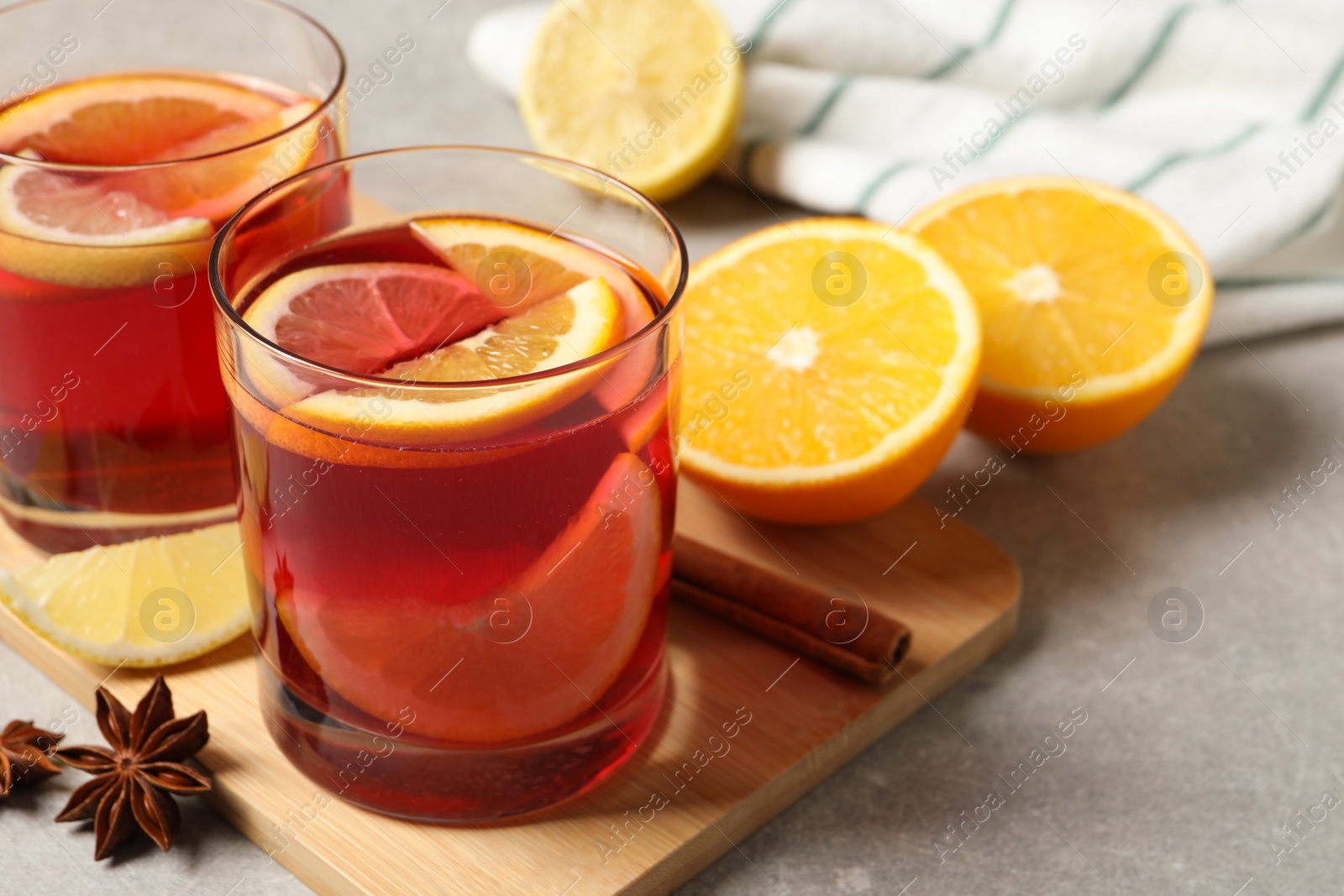 Photo of Aromatic punch drink and ingredients on light grey table, space for text