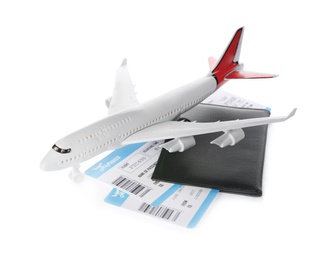Toy airplane and passport with tickets on white background