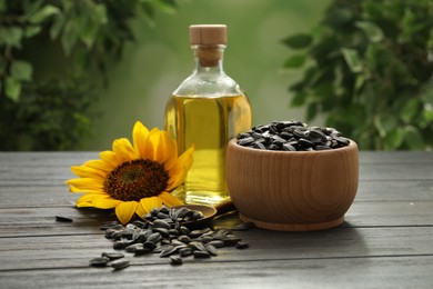 Photo of Sunflower, bottle of oil and seeds on wooden table against blurred background