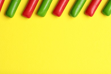 Many tasty bubble gums on yellow background, flat lay. Space for text