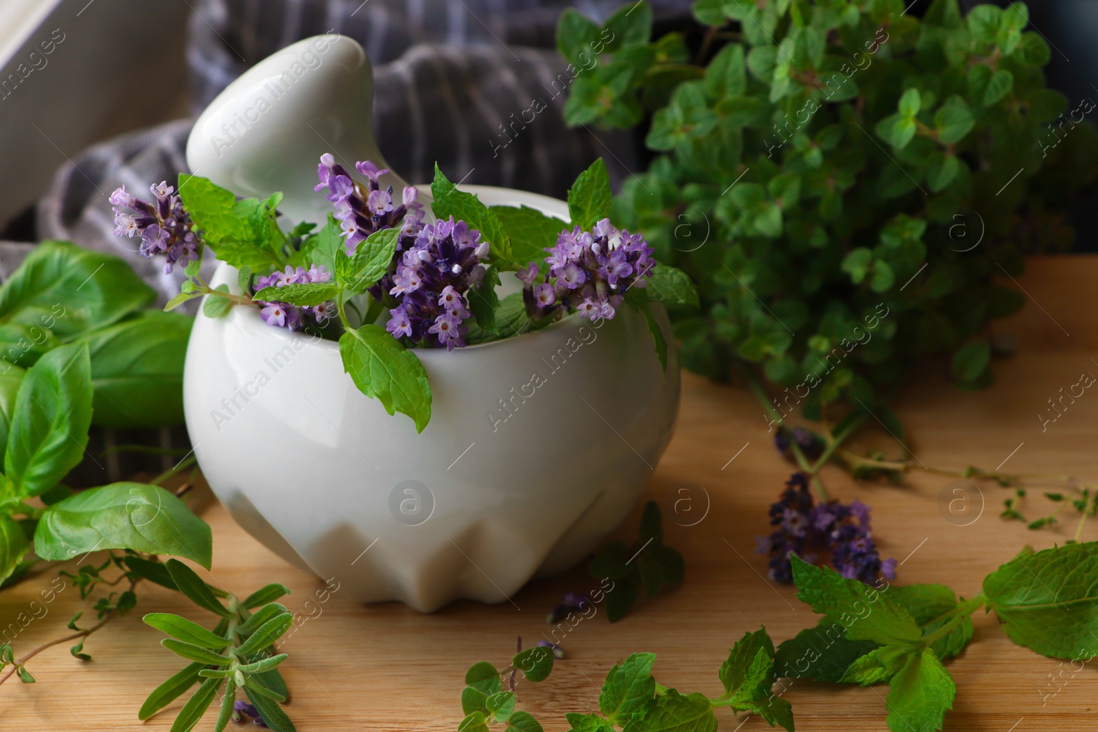 Photo of Mortar with fresh lavender flowers, mint and pestle on wooden table