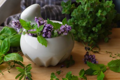 Mortar with fresh lavender flowers, mint and pestle on wooden table