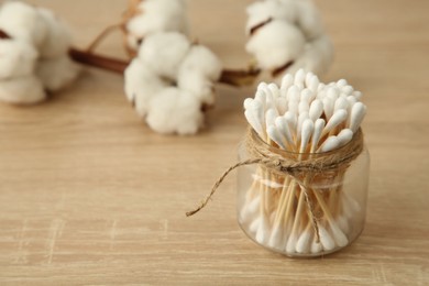 Photo of Cotton swabs and flowers on wooden table, closeup. Space for text