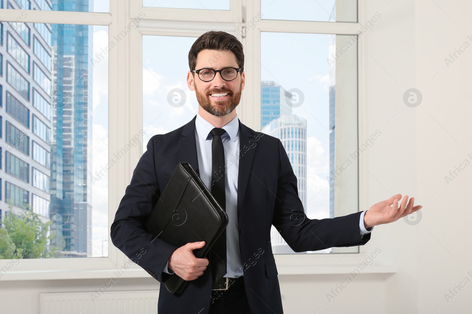 Photo of Handsome real estate agent with documents indoors