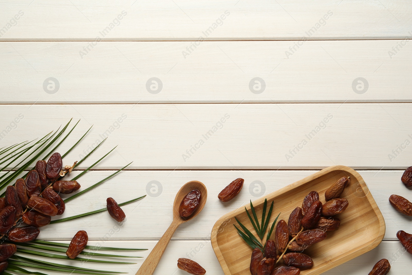 Photo of Flat lay composition with tasty sweet dried dates on white wooden table. Space for text