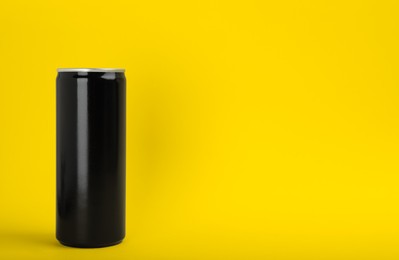 Black can of energy drink on yellow background. Space for text