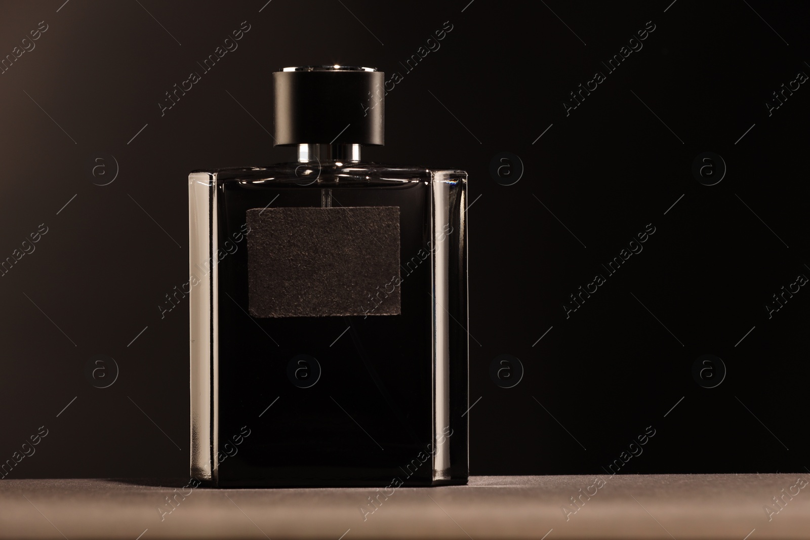 Photo of Luxury men`s perfume in bottle on grey table against dark background, space for text