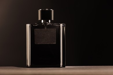 Luxury men`s perfume in bottle on grey table against dark background, space for text