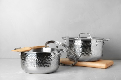 Photo of New clean saucepans on table against grey background, space for text