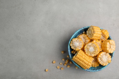 Photo of Bowl with tasty sweet corn on grey background, top view