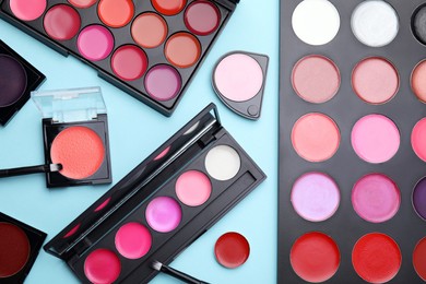 Flat lay composition with cream lipstick palettes on light turquoise background. Professional cosmetic product