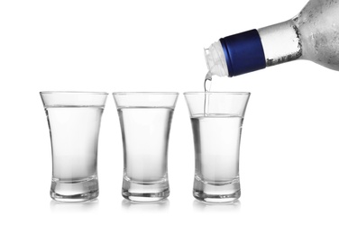 Photo of Pouring cold vodka into shot glass on white background