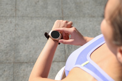 Woman checking fitness tracker after training outdoors, closeup