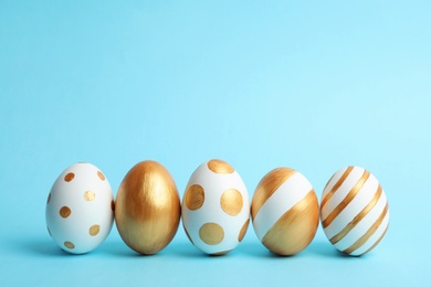 Photo of Line of traditional Easter eggs decorated with golden paint on color background