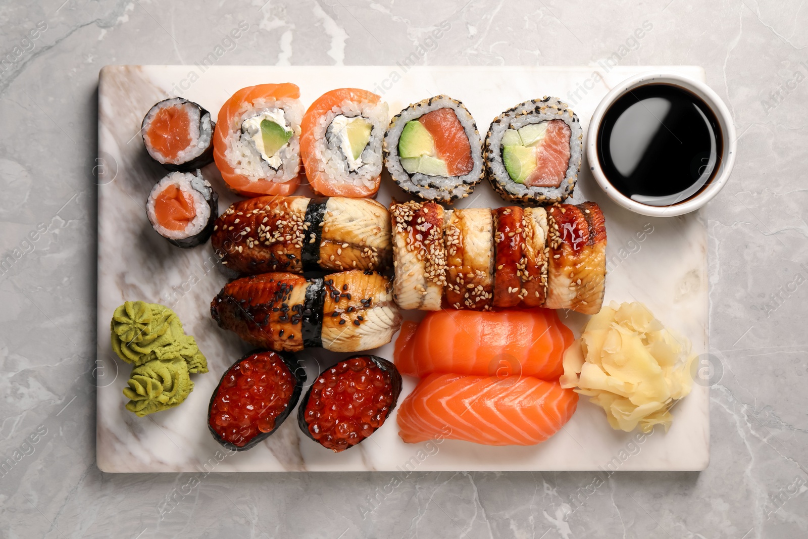 Photo of Set of tasty sushi rolls on light grey marble table, top view