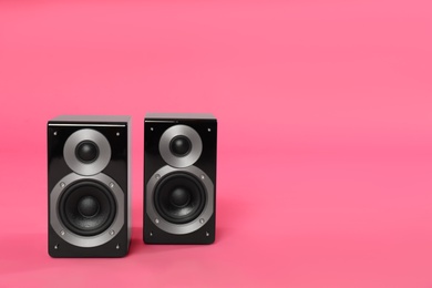 Modern powerful audio speakers on pink background, space for text