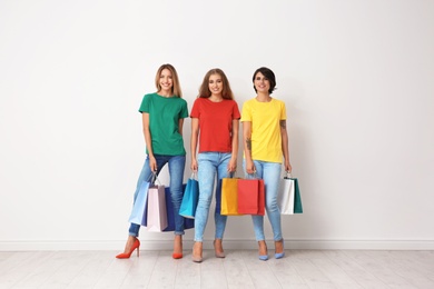 Photo of Group of young women with shopping bags near light wall