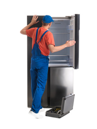 Photo of Male technician repairing refrigerator on white background