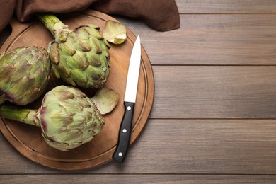 Photo of Fresh raw artichokes on wooden table, top view. Space for text