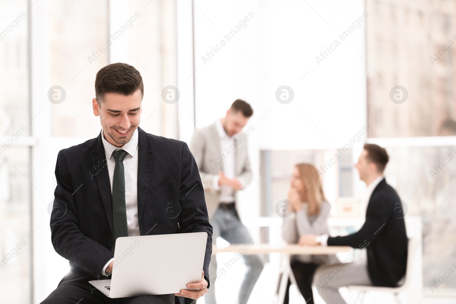 Photo of Portrait of handsome young businessman with laptop in office