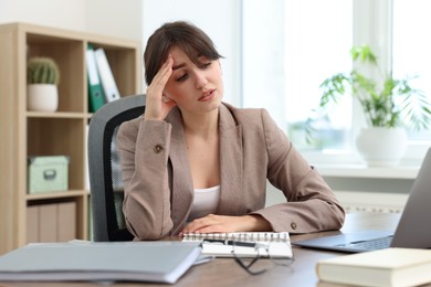 Overwhelmed office worker sitting at table with laptop indoors