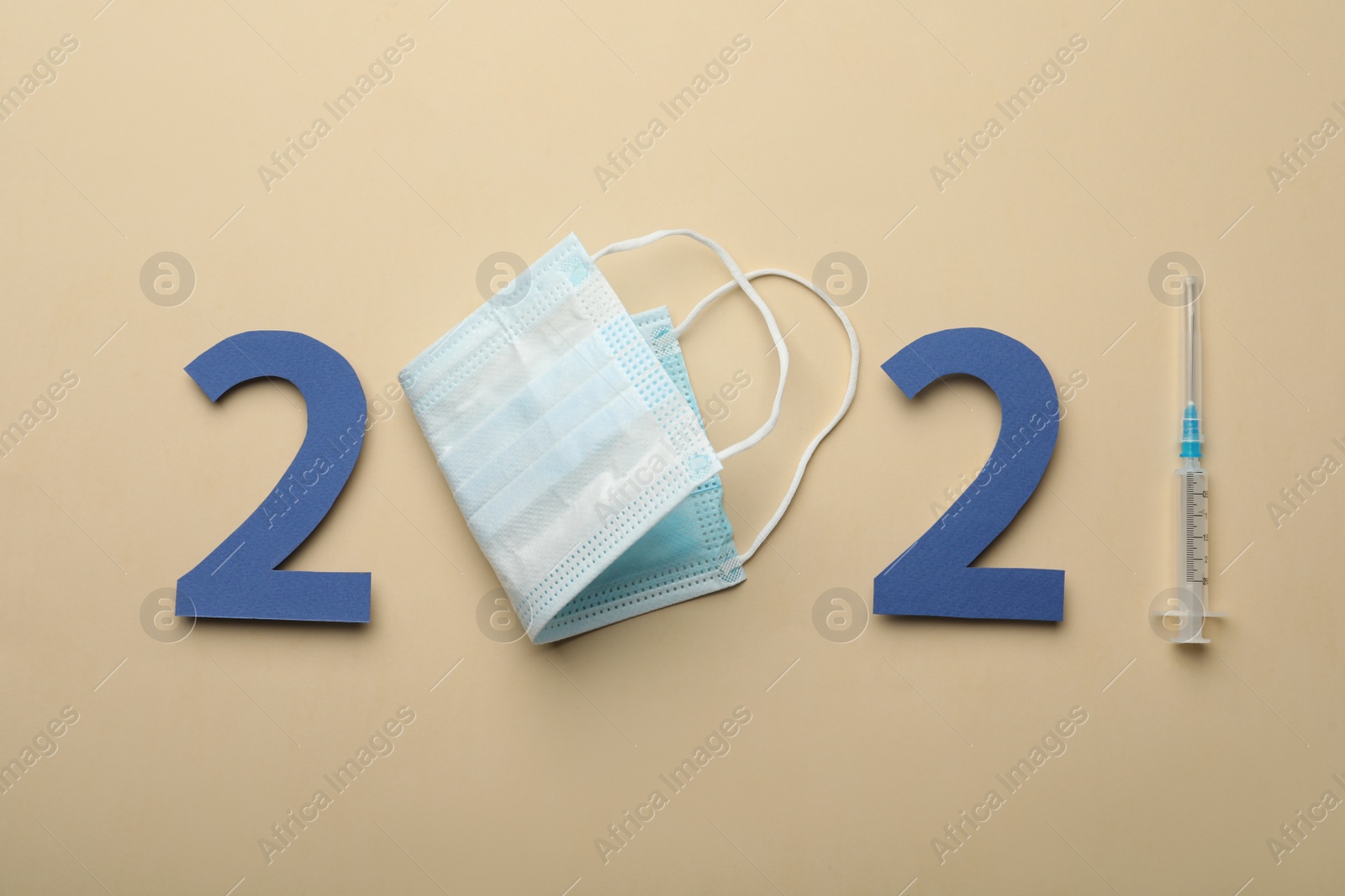 Photo of Paper numbers, medical mask and syringe forming 2021 on beige background, flat lay. Coronavirus vaccination