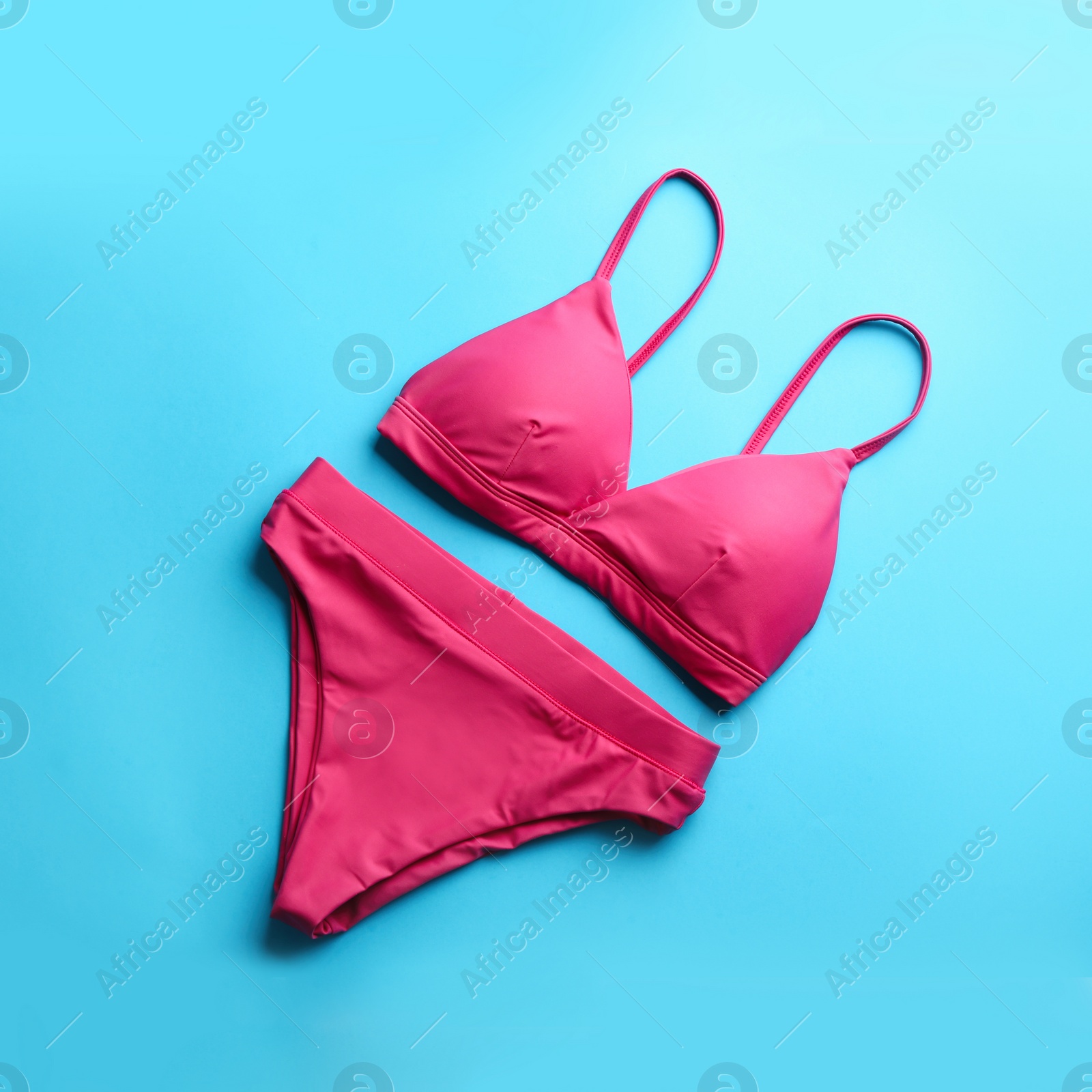 Photo of Beautiful pink bikini on light blue background, top view