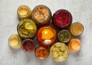 Many jars with different preserved products on white table, flat lay