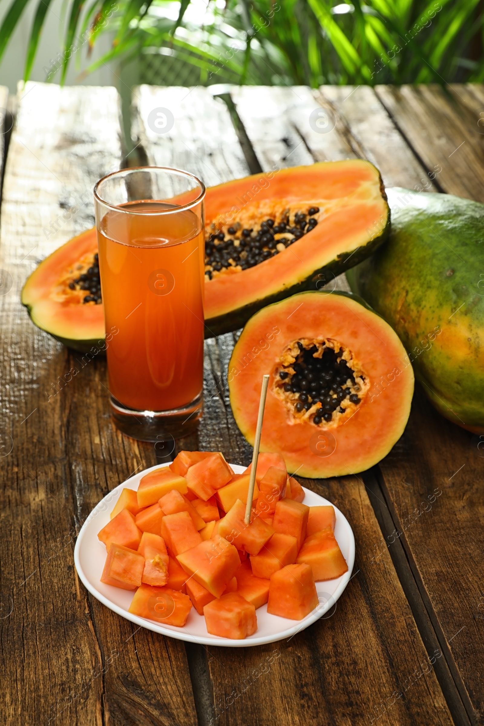 Photo of Fresh papayas and juice on wooden table