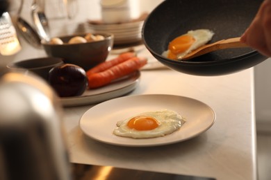 Photo of Man putting cooked eggs on plate from frying pan, closeup