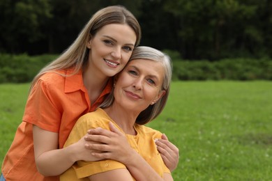 Photo of Happy mature mother and her daughter hugging in park
