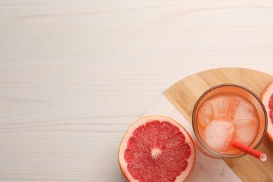 Photo of Tasty freshly made grapefruit juice and fruit on white wooden table, top view. Space for text